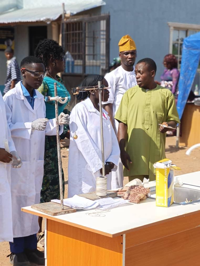 Students in lab coats demonstrating a weights and balance experiment at the science fair